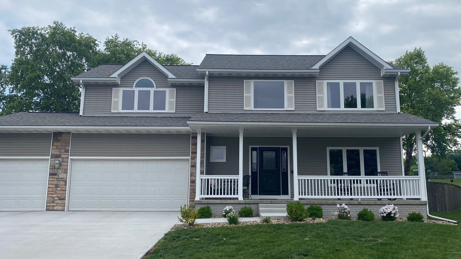 A two-story house featuring new Panes Premium Vinyl windows with white trim, installed in Johnston, Iowa