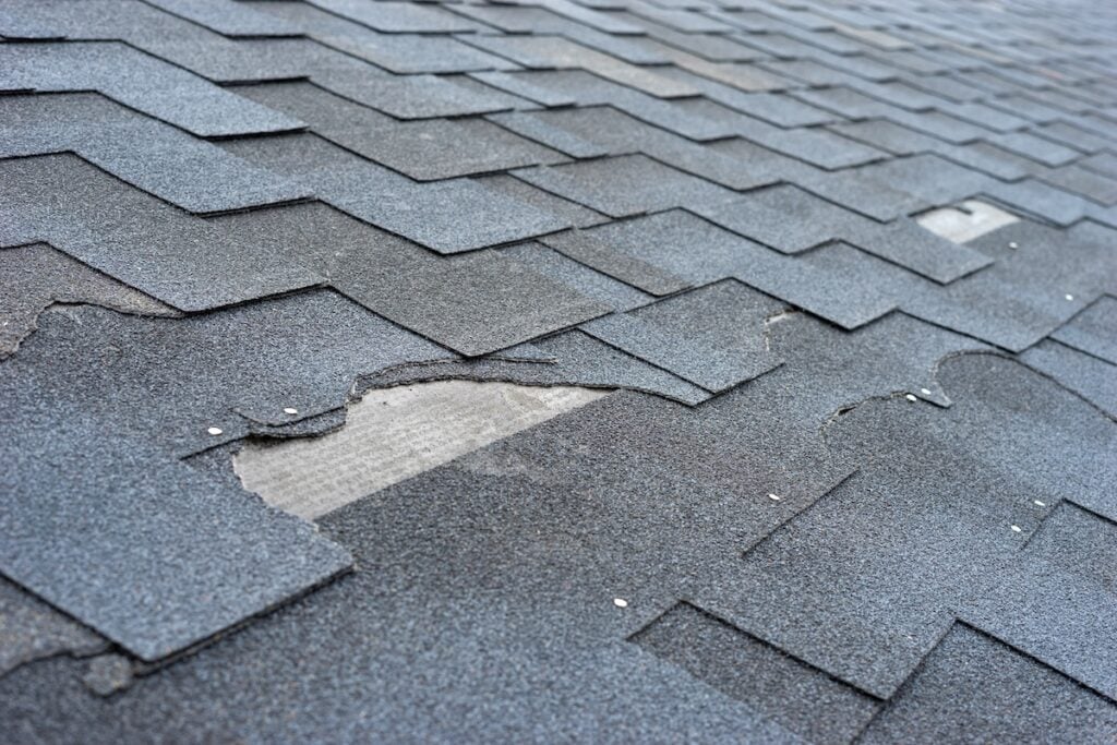 Сlose up view of asphalt shingles roof hail damage that needs repair.
