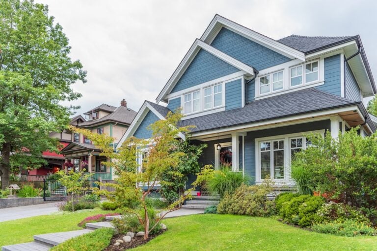 Nice blue house with a gray roof and white window trims in a suburban neighborhood.
