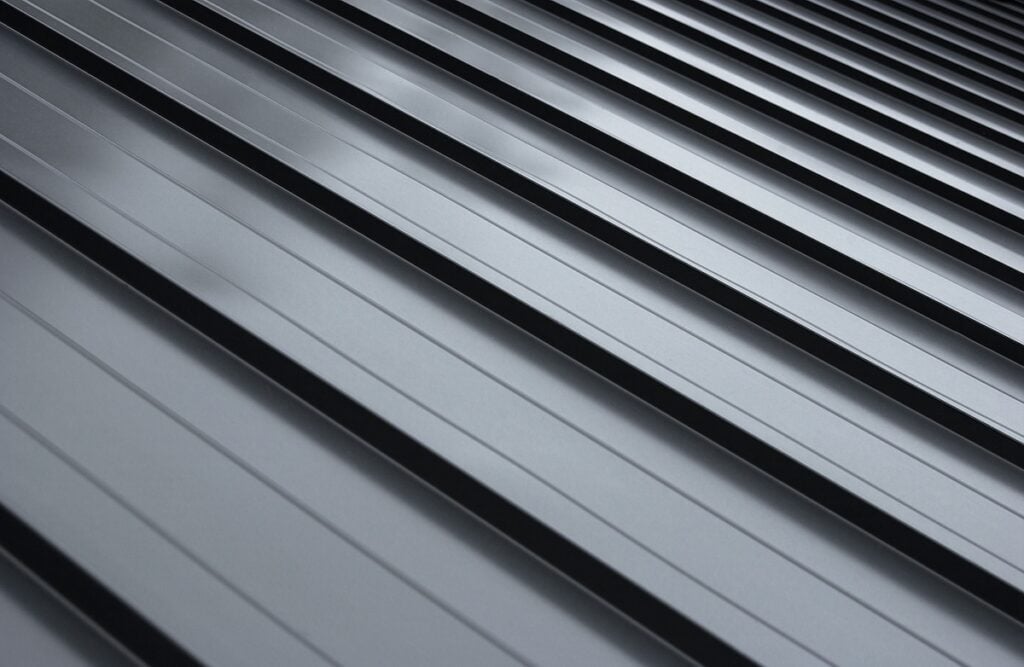 Close-up house retro roof panel with standing seam and fasteners. Classic style black metal panel with rebate joint. Modern galvanized steel roofing sheet with ribs. 
